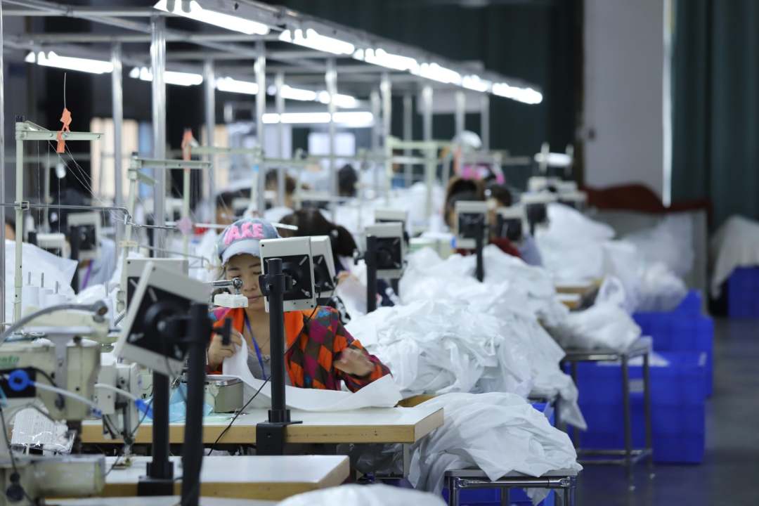  圖為工廠內(nèi)工人縫制衣物，一派繁忙景象。