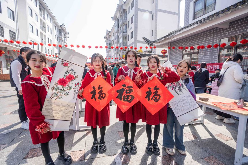 小朋友們展示現(xiàn)場領(lǐng)取的春節(jié)字畫。羅大富攝