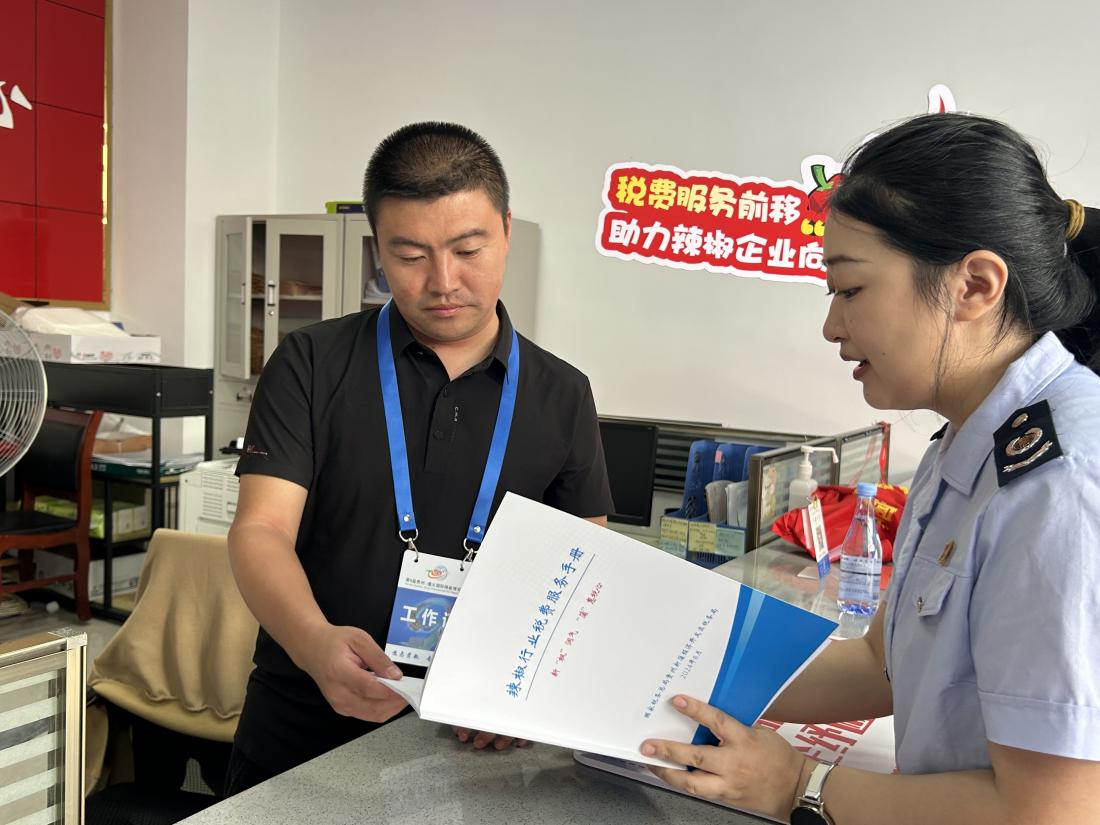 稅務(wù)干部為辣椒企業(yè)送上辣椒行業(yè)稅費(fèi)服務(wù)手冊(cè)。周萬(wàn)青攝