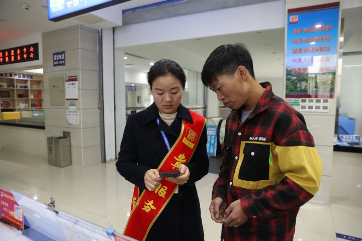 劍河縣政務(wù)服務(wù)中心工作人員正在幫助群眾手機線上操作業(yè)務(wù)辦理。