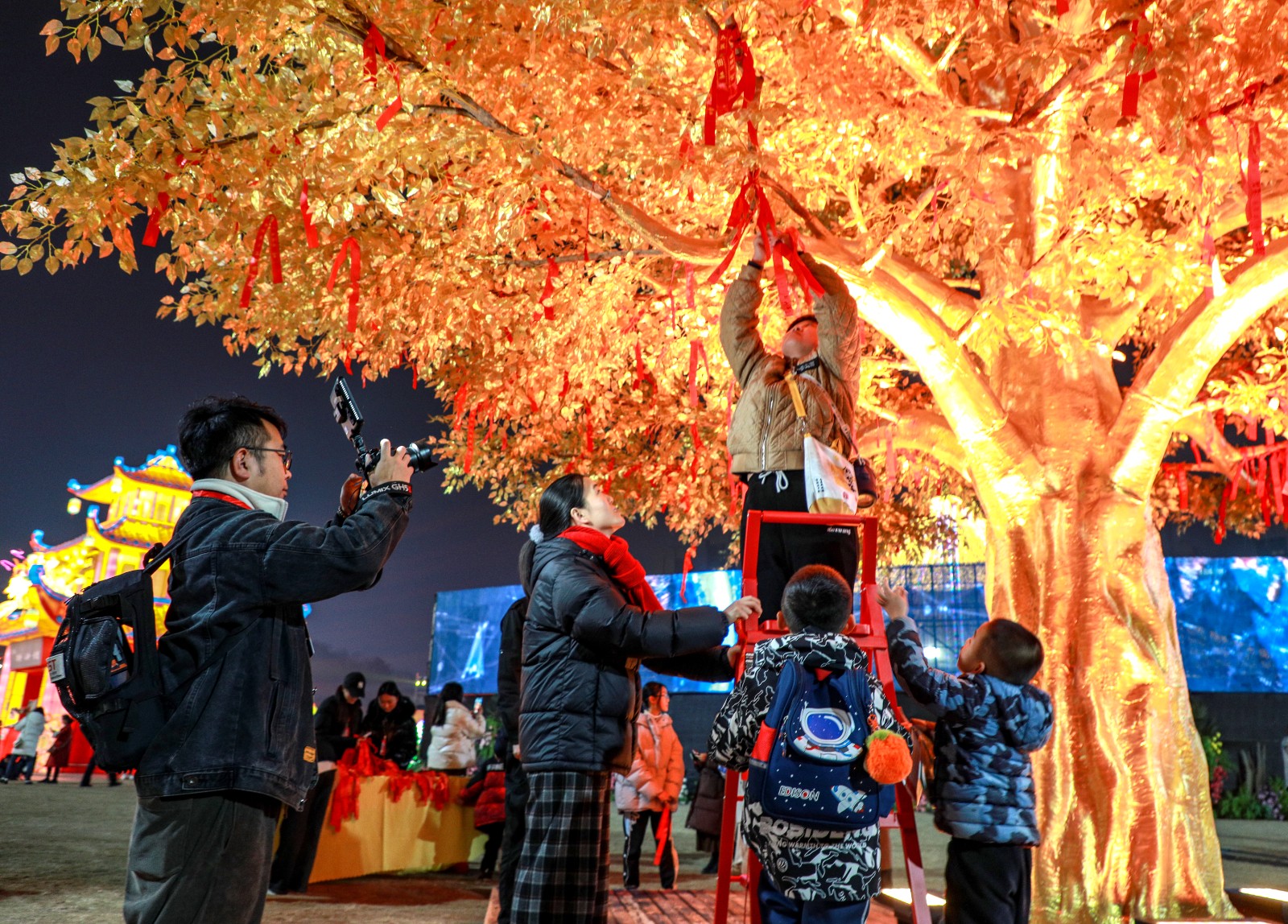 游客將寫好的新年祝福掛到祈福樹上。