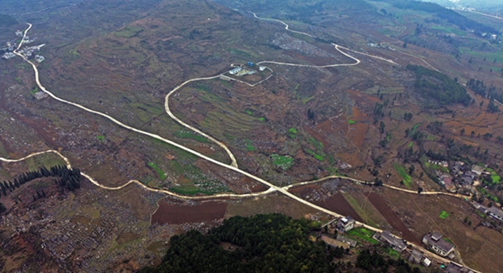 航拍貴州省黔西市鐵石苗族彝族鄉(xiāng)鐵盔山村的機耕道與村莊、山巒、田地構成一幅生機盎然的田園畫卷。  熊軍萬攝