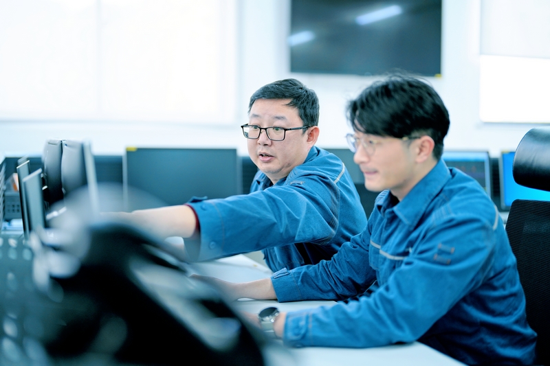 周敬余（左）給新員工講解監(jiān)控信號的作用。陳濤攝